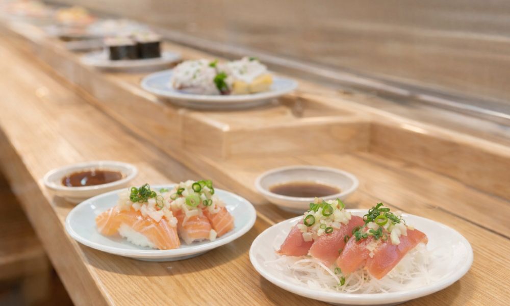 回転寿司の寿司皿のイメージ。サーモンやマグロなどさっぱりしたネタが並ぶ食事シーン