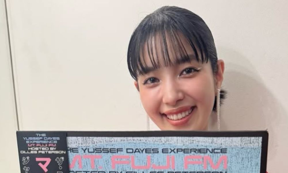 城南海が笑顔でアルバムを手に持ち、カメラに向かってポーズをとるポートレート