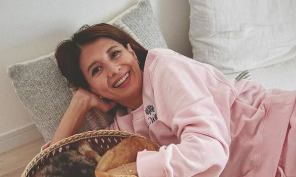 吉川ひなのさんの2025年のインスタ投稿画像。ピンクのスウェット姿でリラックスしながら横になり、笑顔でくつろぐ自然体の様子。