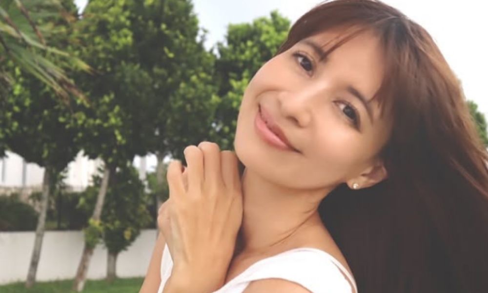 吉川ひなのの現在の姿。屋外の自然の中で、ナチュラルな笑顔と落ち着いた大人の雰囲気が印象的なポートレート。