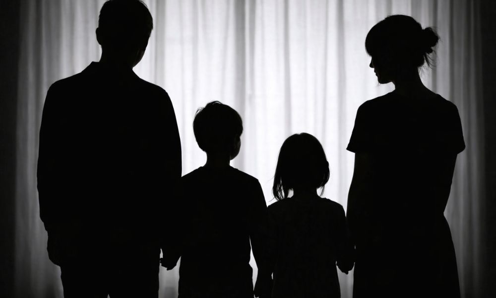 家族4人の後ろ姿シルエット（手をつないで並ぶ親子のイメージ、家庭構成を表現）