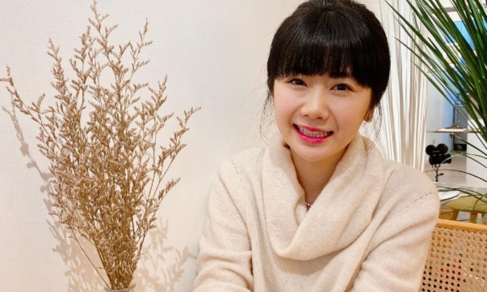 福原愛が室内で微笑みながらカメラに向かって座っている様子の写真